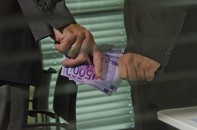 Midsection of business people holding paper currencies