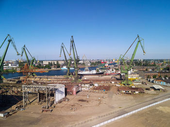 Cranes at harbor against clear blue sky