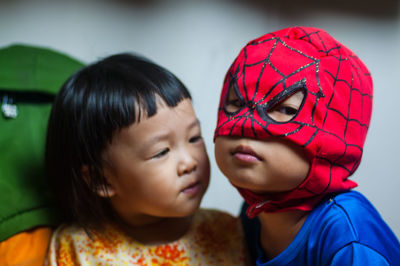 Close-up of boy in superman costume with sister at home