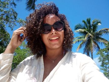 Portrait of smiling young man wearing sunglasses against sky