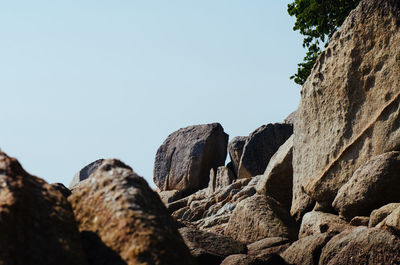 Low angle view of rocks against clear blue sky