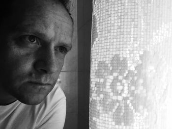 Close-up of mid adult man looking through window at home
