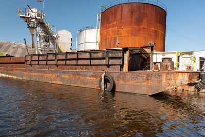 View of factory by river against sky