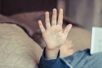 High angle view of boy showing stop sign while lying on bed at home