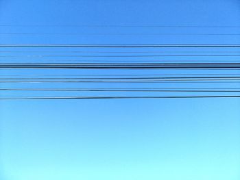 Low angle view of power lines against blue sky