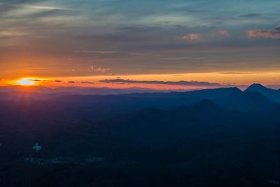 Scenic view of silhouette mountains against orange sky