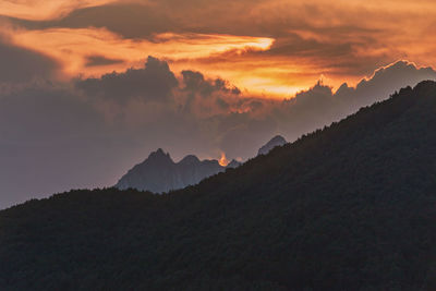 Scenic view of mountains against dramatic sky during sunset