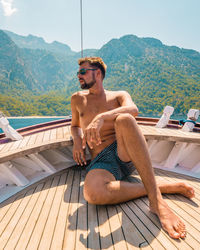 Young man sitting in boat against mountain