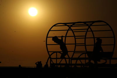 Silhouette people standing against orange sky during sunset