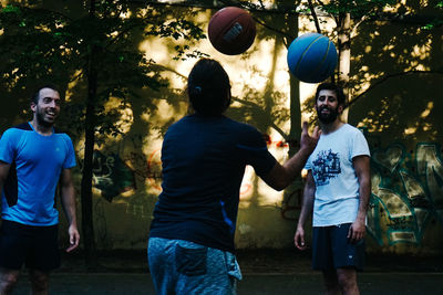 Men playing with balloons against trees