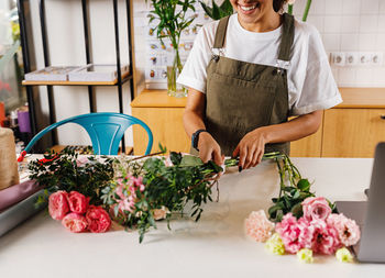 Midsection of smiling florist making bouquet on table