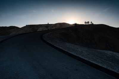 Scenic view of road by silhouette mountain against sky