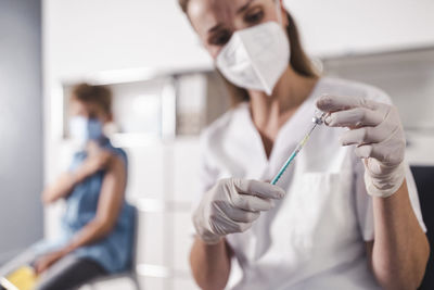 Nurse injecting syringe in vial at vaccination center