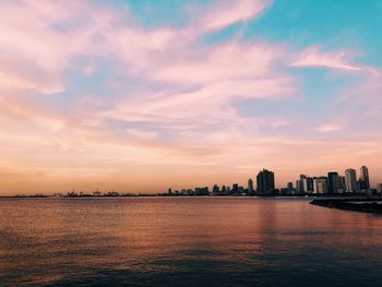 Scenic view of sea and buildings against sky during sunset
