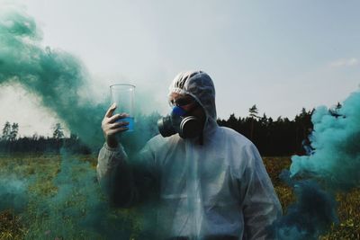 Rear view of man standing by glass on field against sky