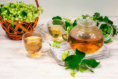 Teapot and two cups of tea with a linden tree on a wooden table. healing tea.