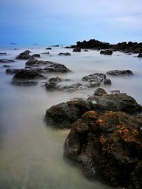Rocks on sea shore against sky