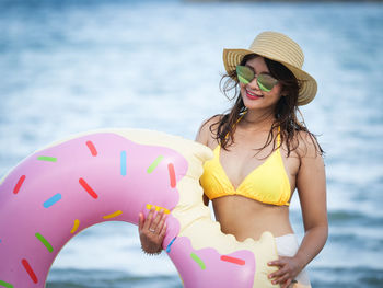Woman with inflatable ring standing against sea