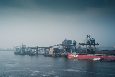 Ship moored at harbor against sky