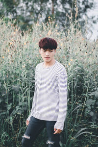 Young man looking down while standing by plants