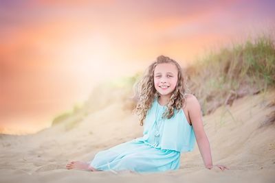 Portrait of smiling girl on sand at sunset