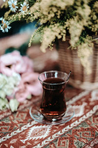 Glass cup of turkish black tea on table with pattern and flowers