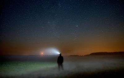 Silhouette person standing on field against sky at night