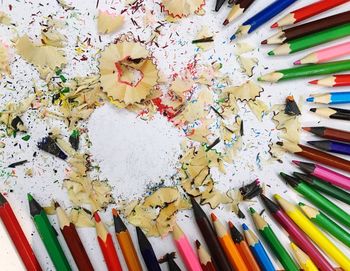 High angle view of colored pencils with shavings on table