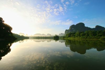 Reflection of trees in lake against cloudy sky