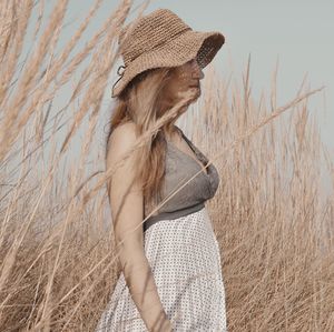 Side view of woman wearing hat standing on field