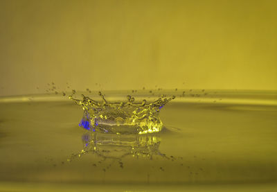 Close-up of water splashing against yellow background