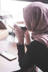 Midsection of woman reading book while sitting on table