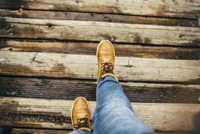 Low section of person wearing shoes on wood