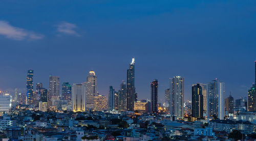 Illuminated modern buildings in city against sky