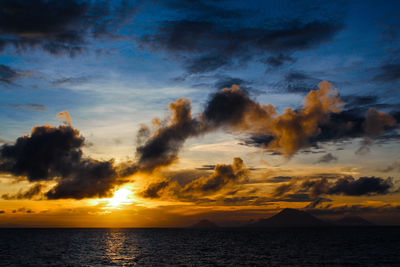 Scenic view of sea against dramatic sky during sunset