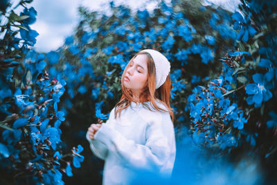 Portrait of young woman standing against plants