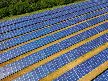 Solar power plant with rows of photovoltaic panels on an agricultural field in sunshine, germany
