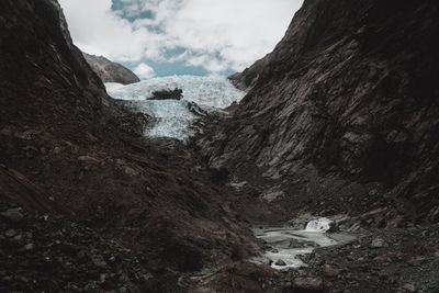 Retreating ice sheet in fox glacier, new zealand with jagged rock walls and a volcanic valley. 