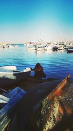 Boats moored at harbor against clear blue sky