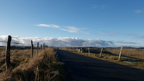 Road amidst field against sky