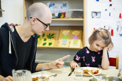 Male teacher scolding girl for not having food in kindergarten