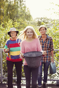 Portrait of three generation females with gardening equipment in yard