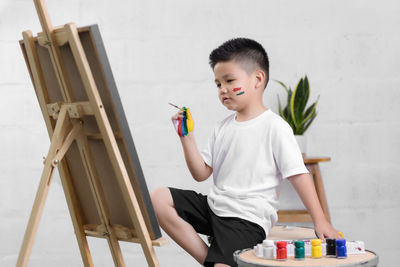 Boy painting at home against wall