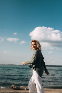Woman standing by sea against sky