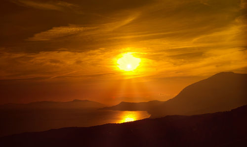 Scenic view of silhouette mountains against romantic sky at sunset