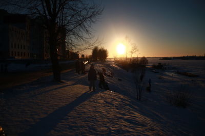 Silhouette people on snow covered landscape during sunset