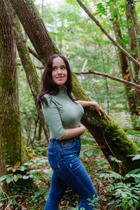 Smiling young woman looking away while standing in forest