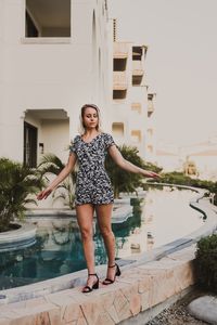 Full length portrait of young woman standing by swimming pool