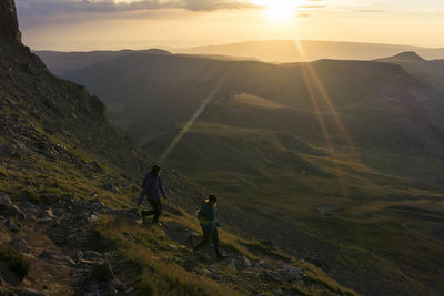 Females hiking on mountain during sunrise