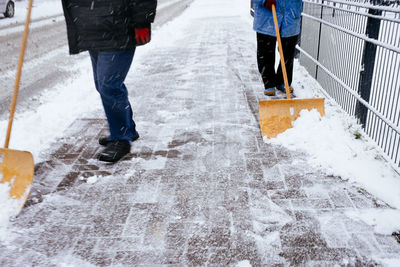 Low section of people walking on snow covered street